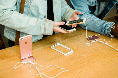 STRASBOURG, FRANCE - APR 9, 2016: Young friends comparing the new Apple SE and iPhone 4 and iPhone 6S phone during the sales launch of the latest Apple Inc. smartphones at the Apple store in Paris, FranceiPhone SE was released on March 31, 2016のeditorial素材