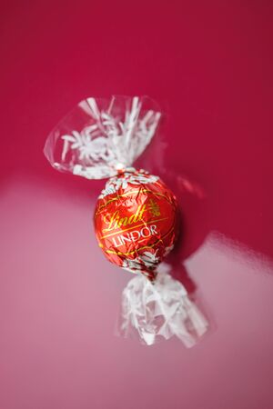 KILCHBERG, SWITZERLAND - MARCH 20, 2014: Lindt Lindor chocolate truffle on a red luxury silk background. Lindt is one one of the lastgest luxury chocolate and confectionery company worldwide with more than 30 factories worldwideのeditorial素材
