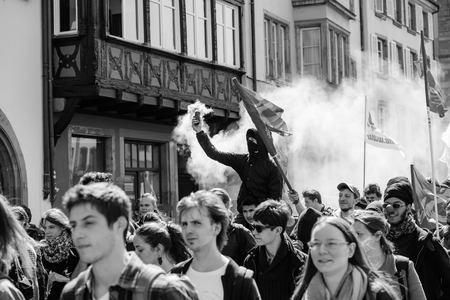 STRASBOURG, FRANCE - APR 20, 2016:Man holding smoke grenade as hundreds of people demonstrate as part of nationwide day of protest against proposed labor reforms by Socialist Governmentのeditorial素材