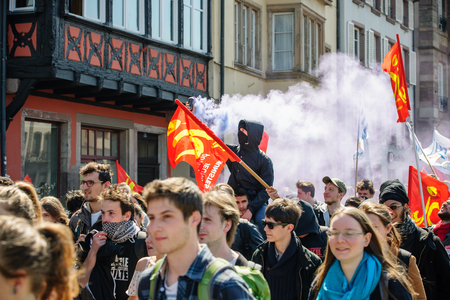 STRASBOURG, FRANCE - APR 20, 2016:Man holding smoke grenade as hundreds of people demonstrate as part of nationwide day of protest against proposed labor reforms by Socialist Governmentのeditorial素材