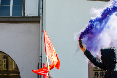 STRASBOURG, FRANCE - APR 20, 2016:Man holding smoke grenade as hundreds of people demonstrate as part of nationwide day of protest against proposed labor reforms by Socialist Governmentのeditorial素材