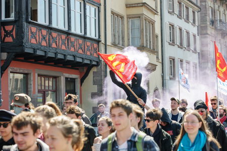 STRASBOURG, FRANCE - APR 20, 2016:Man holding smoke grenade as hundreds of people demonstrate as part of nationwide day of protest against proposed labor reforms by Socialist Governmentのeditorial素材