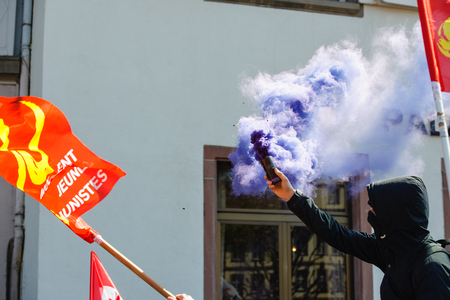 STRASBOURG, FRANCE - APR 20, 2016:Man holding smoke grenade as hundreds of people demonstrate as part of nationwide day of protest against proposed labor reforms by Socialist Governmentのeditorial素材