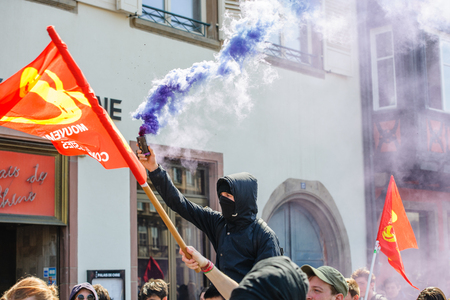 STRASBOURG, FRANCE - APR 20, 2016:Man holding smoke grenade as hundreds of people demonstrate as part of nationwide day of protest against proposed labor reforms by Socialist Governmentのeditorial素材