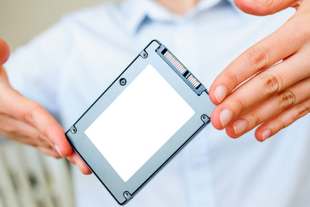 Hands holding fast flash SSD - solid state drive with sata 6 gb connection - blacnk place for diverse informateion and text to be insertedの写真素材