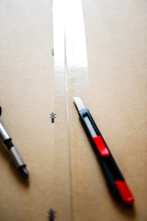 Cutter and screwdriver on box of furniture just above the scotch protection tapeの写真素材