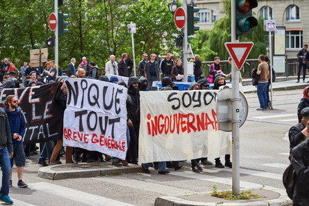 STRASBOURG, FRANCE - MAY 19, 2016: Group of youg people with covered faces holding placards walk with crowd during a demonstrations against proposed French government's labor and employment law reformのeditorial素材