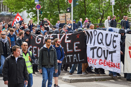 STRASBOURG, FRANCE - MAY 19, 2016: Group of youg people with covered faces holding placards walk with crowd during a demonstrations against proposed French government's labor and employment law reformのeditorial素材
