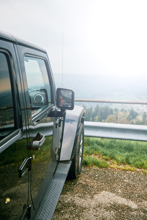 Off-road jeep car travel on mountain road, parked near a beautiful overview over the forestの写真素材