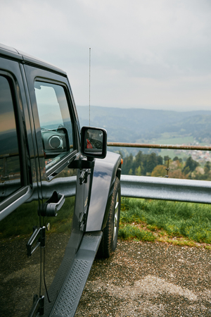 Off-road jeep car travel on mountain road, parked near a beautiful overview over the forestの写真素材