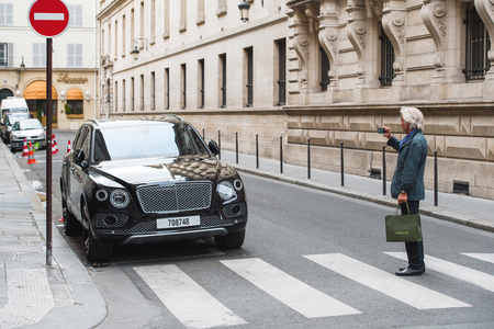 PARIS, FRANCE - MAY 21, 2016: Man taking photo of the luxury Bentley Bentayga Hybrid SUV on the streets of Paris, Franceのeditorial素材