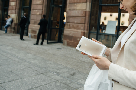 PARIS, FRANCE - SEPTEMBER 16, 2016: Woman in front of Apple Store looking at the New Apple iPhone 7 Plus box right after purchase on the date of worldwide launch. being tested by woman after purchase. New Apple iPhone tends to become one of the most populのeditorial素材