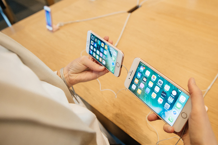 PARIS, FRANCE - SEPTEMBER 16, 2016: New Apple iPhone 7 being tested by woman after purchase - comparing the both iPhone 7 and iPhone 7 Plus in terms of size and specs. New Apple iPhone tends to become one of the most popular smart phones in the world in 2のeditorial素材
