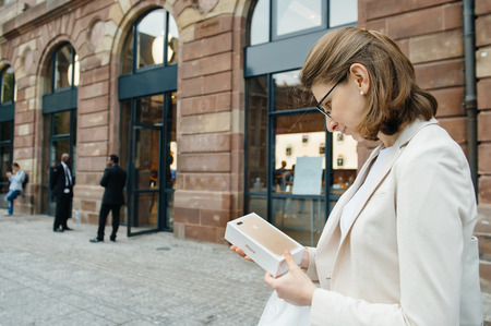 PARIS, FRANCE - SEPTEMBER 16, 2016: Woman in front of Apple Store looking at the New Apple iPhone 7 Plus box right after purchase on the date of worldwide launch. being tested by woman after purchase. New Apple iPhone tends to become one of the most populのeditorial素材