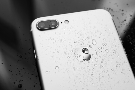 PARIS, FRANCE - SEP 26, 2016: New Apple iPhone 7 Plus unboxing and testing - water drops on rear - studio shot. New iPhone7 is one of the best waterproof smart phone in the worldのeditorial素材