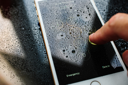 PARIS, FRANCE - SEP 26, 2016: New Apple iPhone 7 Plus unboxing and testing - man unlocking iPhone passcode under rain. New iPhone7 is one of the best waterproof smart phone in the worldのeditorial素材
