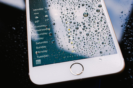 PARIS, FRANCE - SEP 26, 2016: New Apple iPhone 7 Plus unboxing and testing - weather app on iPhone screen with forecast. New iPhone7 is one of the best waterproof smart phone in the worldのeditorial素材