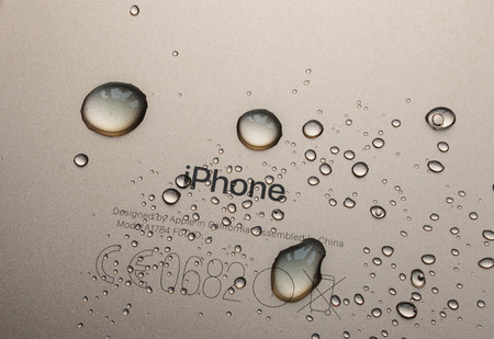 PARIS, FRANCE - SEP 26, 2016: New Apple iPhone 7 Plus unboxing and testing - iPhone engraved logo covered with rain drops. New iPhone7 is one of the best waterproof smart phone in the worldのeditorial素材