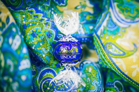 KILCHBERG, SWITZERLAND - MARCH 20, 2014: Lindt Lindor chocolate truffle on a red luxury blue floral background. Lindt is one one of the lastgest luxury chocolate and confectionery company worldwide with more than 30 factories worldwideのeditorial素材
