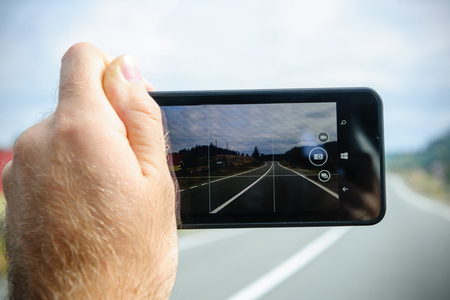 BRASOV, ROMANIA - NOV 1, 2014: man holding microsoft lumia phone in front of highway before taking photoのeditorial素材