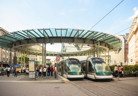 STRASBOURG, FRANCE - APR 7, 2016: Busy center of the French city of Strasbourg, Alsace with two tramways and lots of commuters pedestrians walking under architectural station l'Homme de Ferのeditorial素材