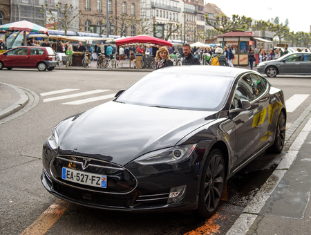 STRASBOURG, FRANCE - MAy 14, 2016: Young couple adimiring the beautiful Tesla Model S car parked in the center of the city - focus is on the carのeditorial素材