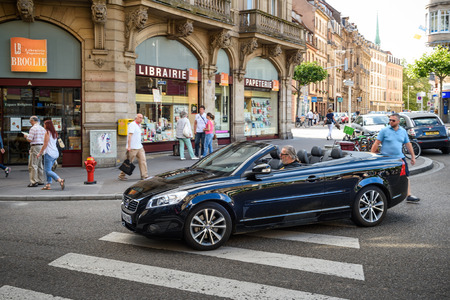 STRASBOURG, FRANCE - APR 7, 2016: Man driving beautiful Volvo C70 Convertible car crossing pedestrian walk in the center of the French city of Strasbourg, Alsace on a summer day with pedestrians and touristsのeditorial素材