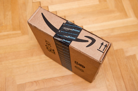 PARIS, FRANCE - JAN 28, 2016: Side view of Amazon Prime logotype printed on cardboard box side seen from above on a wooden parwuet floor. Amazon is an American electronic e-commerce company distribution worlwideのeditorial素材