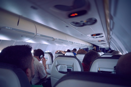 GERMANY - CIRCA 2015: People traveling in airplane - reading books, magazines, listening to the music, preparing to land at destination airportのeditorial素材
