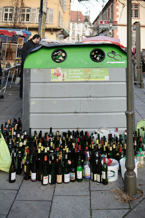 STRASBOURG, FRANCE -  DEC 15, 2013: Multiple wine and beer bottles near glass recycle bin in urban enviroment in the french city of Strasbourg, Franceのeditorial素材