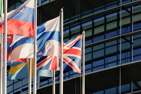 United Kingdom of Great Britain and Northern Ireland or Union Jack flag against front glass facade of European Parliamentの写真素材