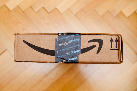 PARIS, FRANCE - JAN 28, 2016: Amazon Prime logotype printed on cardboard box side seen from above on a wooden parwuet floor. Amazon is an American electronic e-commerce company distribution worlwideのeditorial素材