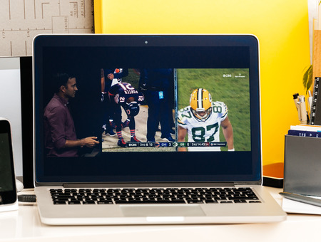 PARIS, FRANCE - OCT 28 2016: Apple Computers website on new MacBook Pro Retina with OLED Touch bar in geek creative room showcasing Apple Keynote presentation of Tv app by Apple Nfl gameのeditorial素材
