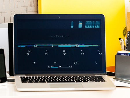 PARIS, FRANCE - OCT 28 2016: Apple Computers website on new MacBook Pro Retina with OLED Touch bar in geek creative room showcasing Apple Keynote presentation of touchbar with Emoji, App integration and shortcutsのeditorial素材