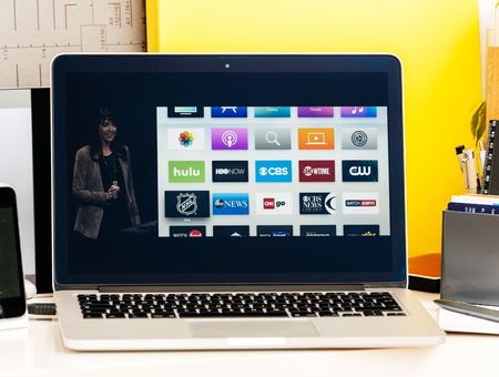 PARIS, FRANCE - OCT 28 2016: Apple Computers website on new MacBook Pro Retina with OLED Touch bar in geek creative room showcasing Apple Keynote presentation of Apple tv Watch now TV app channels movies and showsのeditorial素材