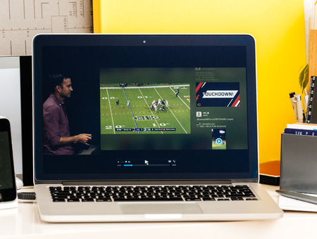 PARIS, FRANCE - OCT 28 2016: Apple Computers website on new MacBook Pro Retina with OLED Touch bar in geek creative room showcasing Apple Keynote presentation of Tv app by Apple Nfl gameのeditorial素材