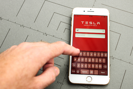 PARIS, FRANCE - SEPT 26, 2016: New iPhone 7 Plus with hand touching screen to sign-in to Tesla Electric car module app. iPhone 7 and iPhone 7 plus is the most wanted phone worldwideのeditorial素材