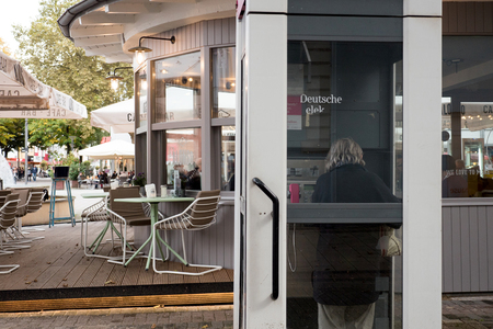 KEHL, GERMANY - OCT 18, 2016: Deutsche Telecom phone booth  with woman calling from phone booth in typical German cityのeditorial素材