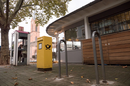 KEHL, GERMANY - OCT 18, 2016: Deutsche Post DHL post box in city with woman calling from phone booth in typical German cityのeditorial素材