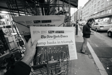 PARIS, FRANCE - NOV 10, 2016: Man buying The New York Times newspaper with shocking headline title at press kiosk about the US President Elections - Donald Trump is the 45th President of United States of Americaのeditorial素材