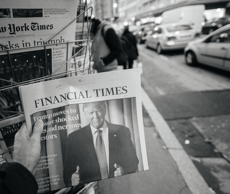 PARIS, FRANCE - NOV 10, 2016: Man buying Financial Times newspaper with shocking headline title at press kiosk about the US President Elections - Donald Trump is the 45th President of United States of Americaのeditorial素材