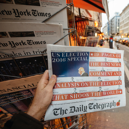 PARIS, FRANCE - NOV 10, 2016: Man buying The Daily Telegraph newspaper with shocking headline title at press kiosk about the US President Elections - Donald Trump is the 45th President of United States of Americaのeditorial素材