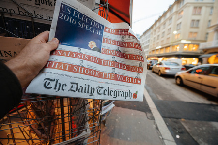 PARIS, FRANCE - NOV 10, 2016: Man buying The Daily Telegraph newspaper with shocking headline title at press kiosk about the US President Elections - Donald Trump is the 45th President of United States of Americaのeditorial素材