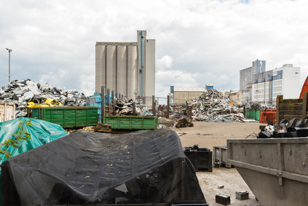 Waste solution dump pile in the yard of a factory with big furnace and processing unit in the background with large clouds and steam from pipes aboveのeditorial素材