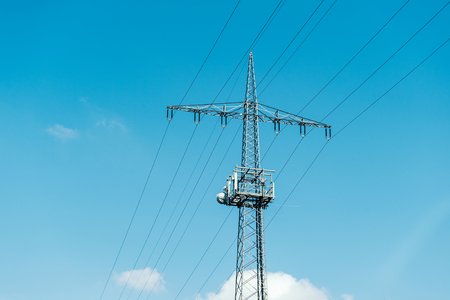 Electrical tower current mast against blue clear sky with  - advertising image for environmentally friendly energy producersの写真素材