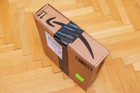 PARIS, FRANCE - JAN 28, 2016: Side view of Amazon Prime logotype printed on cardboard box side seen from above on a wooden parwuet floor. Amazon is an American electronic e-commerce company distribution worlwideのeditorial素材