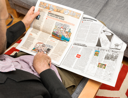 PARIS, FRANCE - NOV 12, 2016: Man reading Charlie Hebdo magazine on after Donal Trump elections as USA President - adminrg cartoon about Arendt Heidigger scandalのeditorial素材
