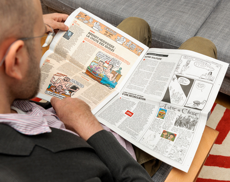 PARIS, FRANCE - NOV 12, 2016: Man reading Charlie Hebdo magazine on after Donal Trump elections as USA President - reading article about our solitudeのeditorial素材
