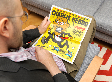 PARIS, FRANCE - NOV 12, 2016: Man reading Charlie Hebdo magazine on after Donal Trump elections as USA President - Barack Obama cartoon running from police officers with gunのeditorial素材