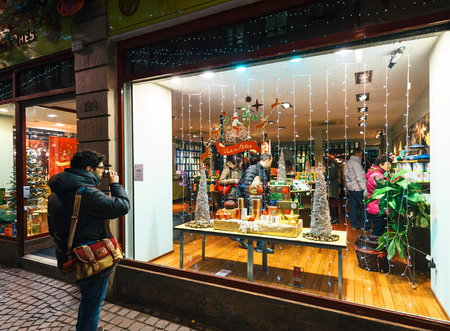 STRASBOURG, FRANCE - DEC 06, 2016: Man drinking hot cup of tea in front of Tea Shop admiring the people buying tea and the Christmas decorations of the window shopping atmosphere drinkのeditorial素材